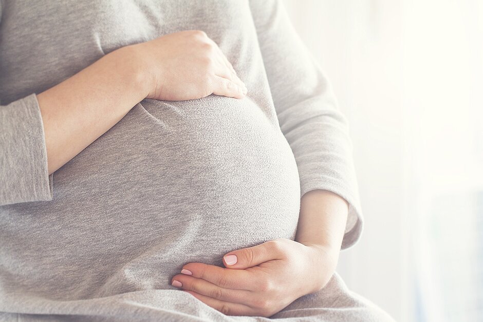 Eine schwangere Frau hält ihren Bauch mit beiden Händen