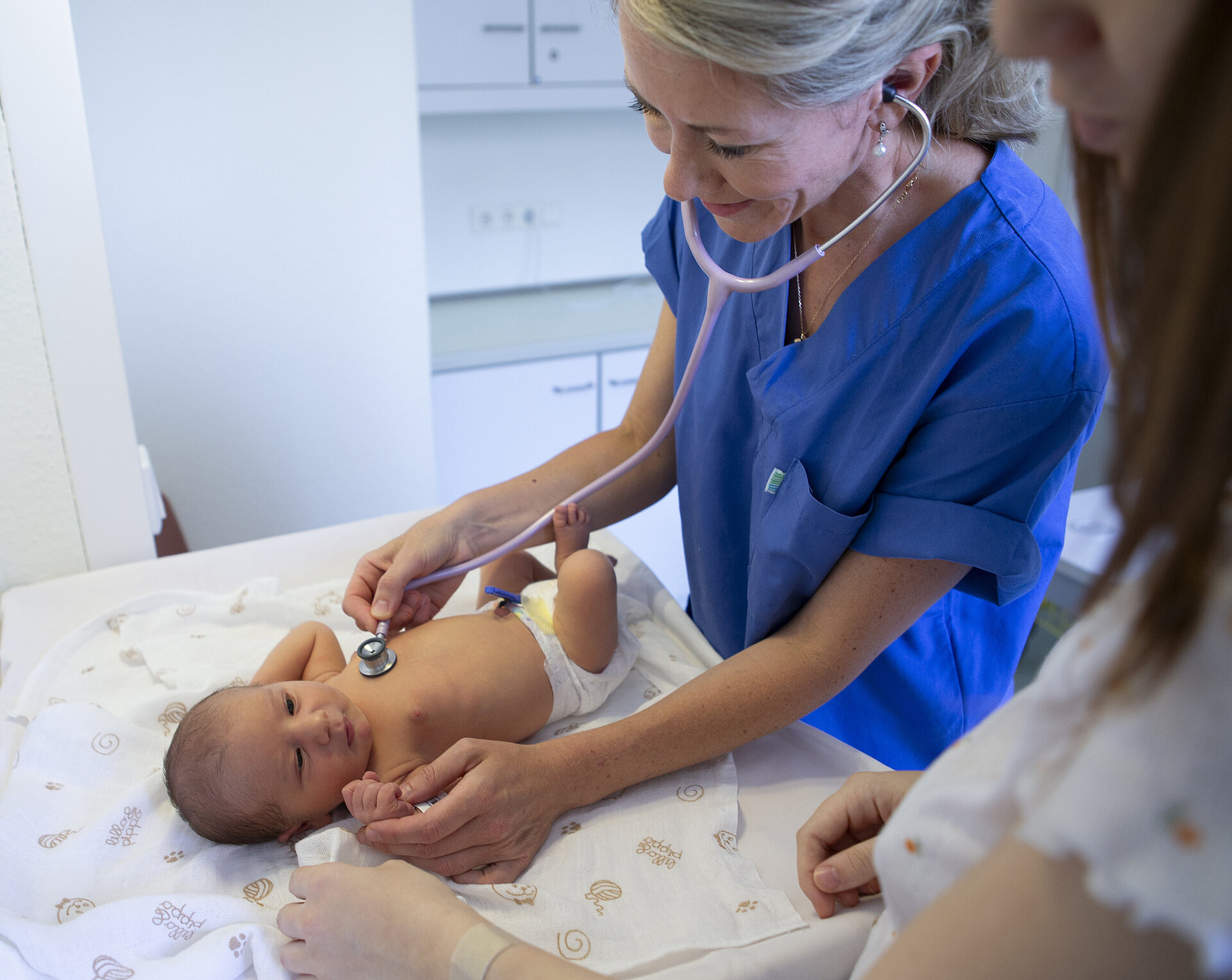 Nach der Schwangerschaft: Eine Ärztin untersucht ein Baby mit einem Stetoskop